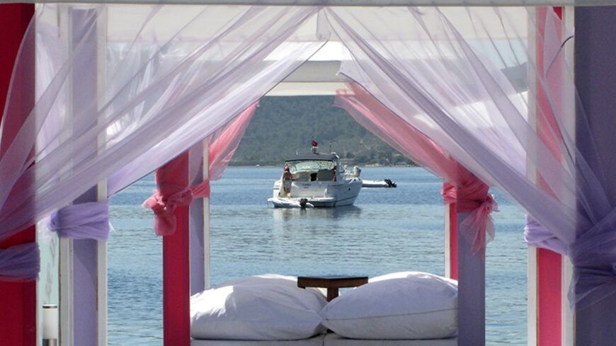 A private boat is seen framed by cushions and tulle curtains at a beach club in Golturkbuku, where luxury hotels lined near the resort town of Bodrum on the southwest Aegean coast of Turkey July 17, 2007. Millions of Turks are postponing their summer holidays or coming home early to vote in elections on Sunday, determined to have a say in the future of this deeply divided Muslim but secular country. To match feature TURKEY-ELECTION/TURNOUT      REUTERS/Fatih Saribas  (TURKEY) - RTR1RYKR