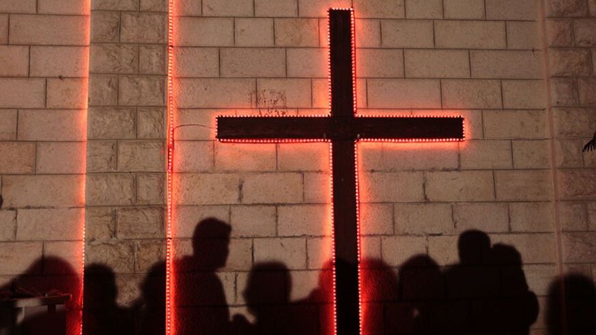 Shadows of Palestinians are cast on a wall with a cross at Gaza's Der Latin church on Christmas Eve December 24, 2009 as they wait for the Christmas mass. Less than 100 Gazans gathered in the church to take part in the Christmas celebrations. REUTERS/Yannis Behrakis (GAZA - Tags: RELIGION POLITICS SOCIETY) - RTR28C3I
