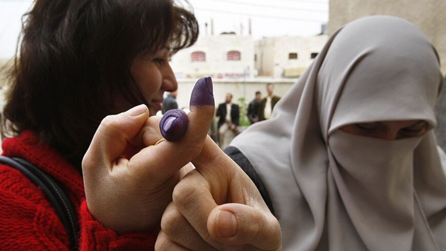 A Muslim (R) and a Christian Iraqi living in Jordan hold up their ink-stained index fingers after casting their ballot at a polling station at a government school in Amman March 5, 2010. Iraqis in Lebanon, Syria and Jordan started early voting ahead of the country's March 7 parliamentary election that will test Iraq's prospects for stability as U.S. troops prepare to leave. REUTERS/Ali Jarekji (JORDAN - Tags: POLITICS ELECTIONS) - RTR2B98I