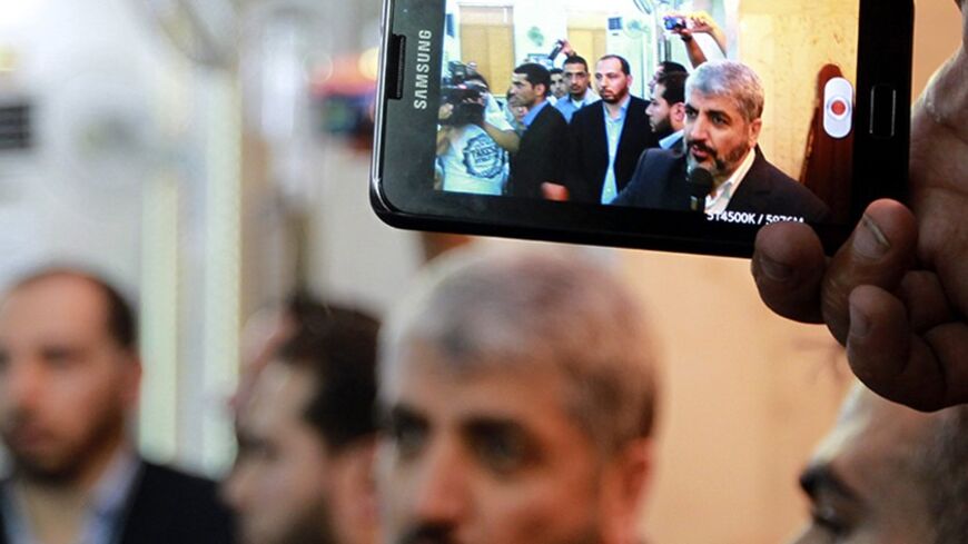 A man uses a mobile phone to record Hamas leader Khaled Meshaal (C) while he speaks during the funeral of Hamas member Kamal Husni Ghanaja in Amman June 29, 2012. Hamas said on Thursday that one of its members, Ghanaja, had been killed in his home in Damascus.  REUTERS/Muhammad Hamed    (JORDAN - Tags: POLITICS) - RTR34D20
