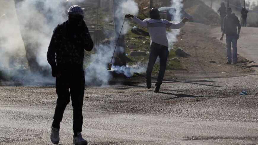 A Palestinian protester uses a sling to throw back a tear gas canister fired by Israeli troops during clashes at Atara checkpoint, north of the West Bank city of Ramallah February 28, 2014. The clashes erupted on Friday following the funeral of Muataz Washaha, who was killed by Israeli forces on Thursday at his home in the West Bank village of Birzeit, near Ramallah. REUTERS/Mohamad Torokman (WEST BANK - Tags: POLITICS CIVIL UNREST) - RTR3FTR8