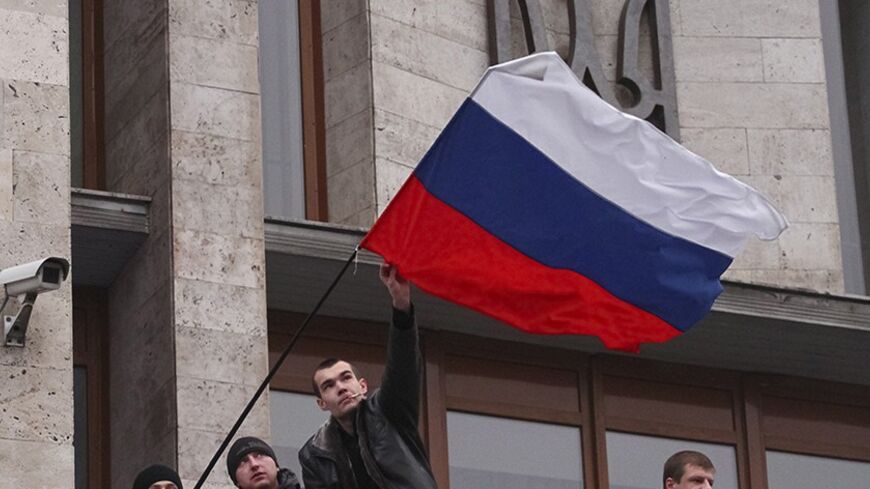 Pro-Russian demonstrators erect a Russian flag outside the regional government building in Donetsk March 5, 2014. Pro-Moscow youths recaptured the administrative headquarters of the eastern city of Donetsk and flew the Russian flag from its roof on Wednesday, hours after Kiev's authorities managed to fly their own flag there for the first time since Saturday.    REUTERS/Stringer  (UKRAINE - Tags: POLITICS CIVIL UNREST) - RTR3G2UQ