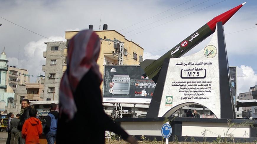A Palestinian girl walks past a monument of a homemade M75 rocket in the middle of a square in Gaza City March 10, 2014. Hamas fired M75 rockets at Tel Aviv and Jerusalem in the 2012 eight-day fighting with Israel.  REUTERS/Mohammed Salem (GAZA - Tags: POLITICS CIVIL UNREST) - RTR3GEHZ