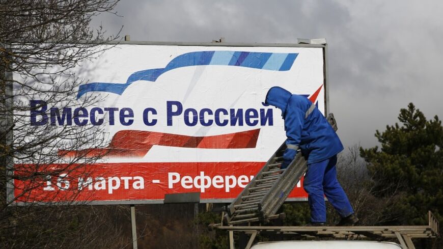 A man puts up a poster calling on Crimea residents to vote in favour of the Ukrainian peninsular joining the Russian federation, at a highway outside of Simferopol March 11, 2014. The poster reads, "Together with Russia. March 16 - referendum".  REUTERS/Thomas Peter (UKRAINE - Tags: POLITICS ELECTIONS) - RTR3GNOI