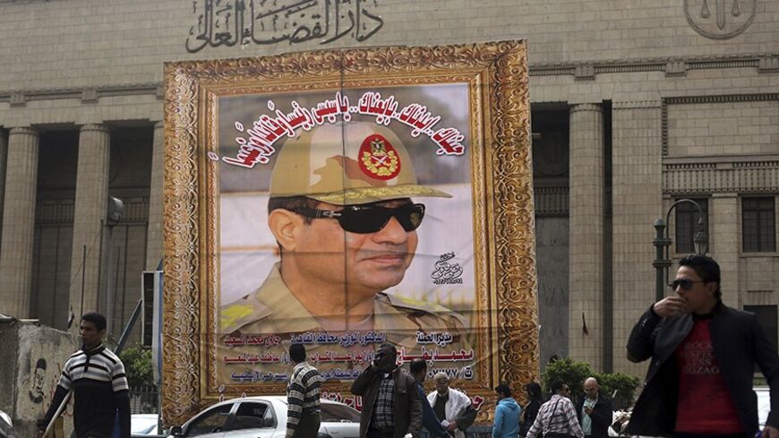 People walk past a huge banner for Egypt's army chief, Field Marshal Abdel Fattah al-Sisi in front of the High Court of Justice in downtown Cairo, March 13, 2014. Cairo's souvenir shops and street stands are filled with memorabilia celebrating al-Sisi. Egypt is pushing ahead with an army-backed plan for political transition, with presidential and parliamentary elections due to take place within months. Sisi is widely expected to announce his presidential bid and win easily. Poster reads, "We love and suppor