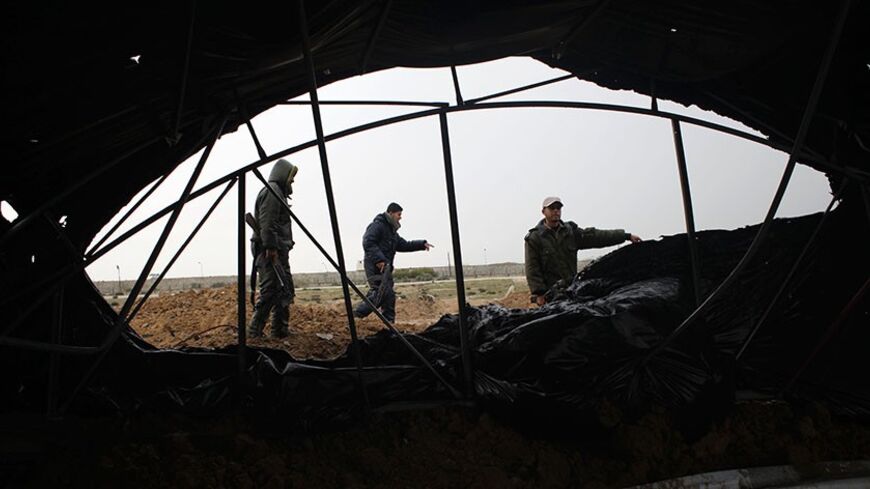 Members of the Palestinian security forces loyal to Hamas inspect the damage after Israeli air strikes on smuggling tunnels in Rafah in the southern Gaza Strip March 13, 2014. Egypt brokered a ceasefire on Thursday aimed at ending a flare-up of rocket attacks from Gaza on Israeli towns and Israeli air strikes in the Palestinian enclave, the Islamic Jihad militant group said. REUTERS/Ibraheem Abu Mustafa (GAZA - Tags: POLITICS CIVIL UNREST) - RTR3GY2E