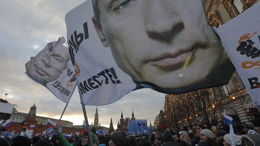 People attend a rally called "We are together" to support the annexation of Ukraine's Crimea to Russia in Red Square in central Moscow, March 18, 2014. Russian President Vladimir Putin, defying Ukrainian protests and Western sanctions, signed a treaty on Tuesday making Crimea part of Russia but said he did not plan to seize any other regions of Ukraine. The flags display portraits of Russia's President Vladimir Putin and read "We are together!" REUTERS/Maxim Shemetov (RUSSIA - Tags: POLITICS TPX IMAGES OF T