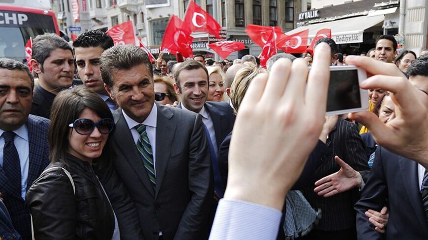 Main opposition Republican People's Party (CHP) mayoral candidate Mustafa Sarigul (3rd L) poses with a woman for a souvenir picture as he walks in the main Istiklal street as part of his election campaign in Istanbul March 27, 2014. To the adulation of the cheering crowds at his election rallies, Prime Minister Tayyip Erdogan paints a picture of an "evil alliance" plotting to topple him and break Turkey. In another place, on another day, his chief rival portrays him as a rogue doomed to jail or exile. Sunda