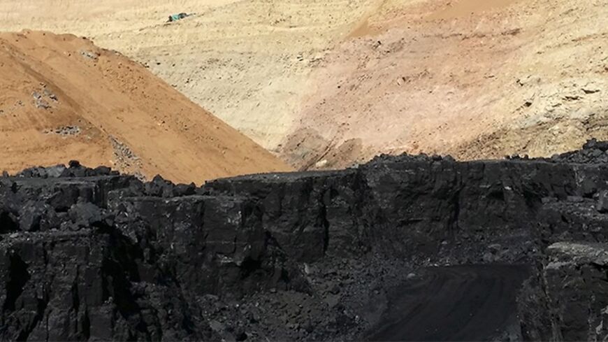 A mine worker looks at stacks of coal in an open-cast steam coal mine located in the Ordos mining district, Inner Mongolia Autonomous Region, March 14, 2014. China's top producing coal province of Inner Mongolia, where Ordos is located, is in crisis. Tumbling prices, caused by weaker demand due to slowing growth in China and a flood of cheaper imports, have forced many smaller miners out of business, while some major firms are slashing wages by up to 50 percent to stem heavy losses. Picture takan March 14, 