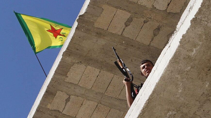 A Kurdish fighter from the Popular Protection Units (YPG) holds his weapon as he takes position atop a building with a YPG flag in Aleppo's Sheikh Maqsoud neighbourhood, June 7, 2013. Kurdish fighters from the YPG joined the Free Syrian Army to fight against forces loyal to Syria's President Bashar al-Assad. Picture taken June 7, 2013. REUTERS/Muzaffar Salman  (SYRIA - Tags: CIVIL UNREST POLITICS CONFLICT) - RTX10USX