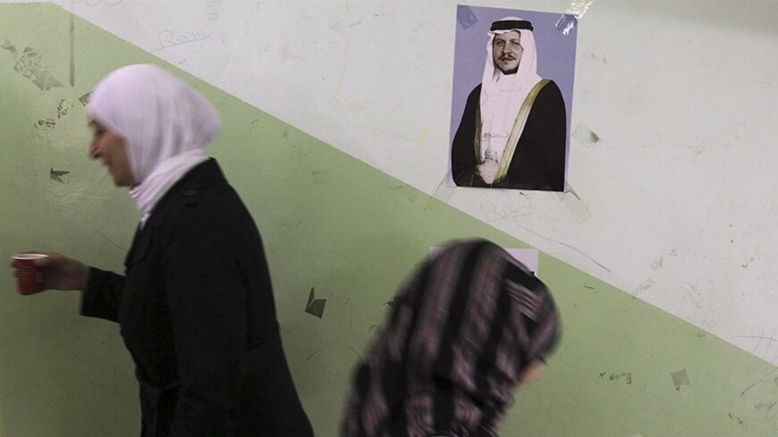 A Jordanian woman walks up stairs past a picture of Jordan's King Abdullah as she goes to cast her ballot for municipal elections at a polling station in Amman August 27, 2013. The Muslim Brotherhood, the main opposition party, is boycotting the polls. REUTERS/Muhammad Hammad (JORDAN - Tags: ELECTIONS POLITICS) - RTX12Y11