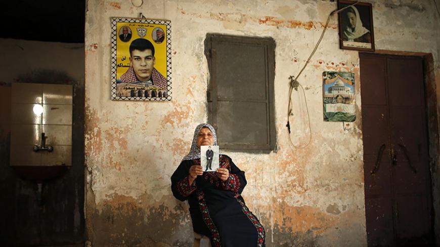The mother of Palestinian prisoner Omar Massoud, who has been held by Israel since 1993, displays to the camera a picture of him ahead of his expected release, at his family's house in Gaza City October 29, 2013. Israelis say Massoud was convicted of killing an Israeli in 1993. Israel is to release 26 Palestinian prisoners in a second stage of a deal brokered by the United States in July that brought a resumption of peace talks. REUTERS/Mohammed Salem (GAZA - Tags: POLITICS CIVIL UNREST CONFLICT) - RTX14SHV
