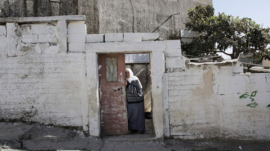 A Palestinian woman stands at the entrance to her house in the Shuafat refugee camp in the West Bank near Jerusalem November 26, 2013. Marooned behind the wall, Israel's controversial barrier, the Shuafat refugee camp reveals the state's uneven treatment of Arab and Jewish neighbourhoods, creating a de facto partition of Jerusalem, which is the epicentre of the Middle East conflict. Picture taken November 26, 2013. REUTERS/Ammar Awad (WEST BANK - Tags: POLITICS SOCIETY) - RTX16PGL