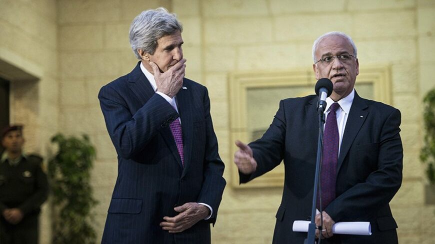 U.S. Secretary of State John Kerry (L) listens as Palestinian negotiator Saeb Erekat speaks to the media after a meeting with Palestinian President Mahmoud Abbas (not pictured) in the West Bank city of Ramallah January 4, 2014. Israel and the Palestinians are making progress towards reaching a framework peace agreement but they are not there yet, Kerry told reporters on Saturday. REUTERS/Brendan Smialowski/Pool (WEST BANK - Tags: POLITICS) - RTX171VX