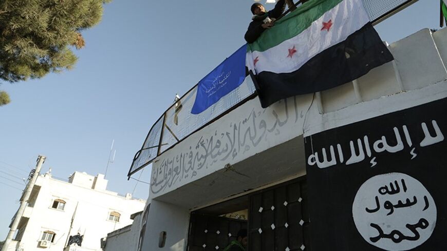 Free Syrian Army fighters erect the Syrian opposition flag atop a former base used by fighters from the Islamic State in Iraq and the Levant (ISIL), after it was captured by rival rebel forces in Manbij town in Aleppo January 8, 2014. An al Qaeda affiliate based in Iraq and Syria has vowed to crush opposition groups it has been confronting in the worst outbreak of infighting among rebels since the start of the uprising against President Bashar al-Assad. Picture taken January 8, 2014. REUTERS/Nashwan Marzouk