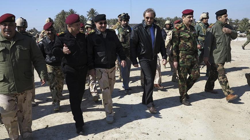 Iraqi acting Defence Minister Saadoun al-Dulaimi (3rd R) walks with army officers during the tour in Anbar province, February 7, 2014.  ISIL militants and other Sunni groups angered by the Shi'ite-led government overran Falluja and parts of the nearby city of Ramadi in the western province of Anbar on Jan. 1. REUTERS/Stringer (IRAQ - Tags: CIVIL UNREST MILITARY) - RTX18DJ1