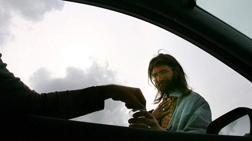 A Russian immigrant begs a driver for spare change in Jerusalem March 26, 2006. A growing number of Israelis live beneath the poverty line, many of them ultra-Orthodox Jews, immigrants and elderly. Poverty is a prominent issue in Israel's campaign for a March 28 parliamentary election. Picture taken March 26, 2006.   REUTERS/Ronen Zvulun - RTR17NNZ