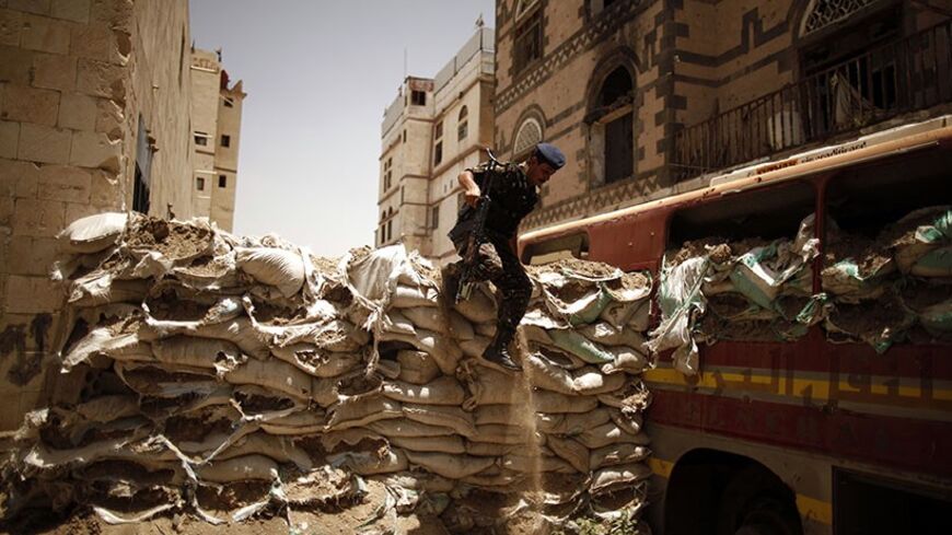 A police trooper jumps over a barricade of sand bags, erected by tribal militants loyal to the powerful al-Ahmar family during last year's fighting with security forces, in Sanaa May 28, 2012. A military committee, set up under a Gulf Cooperation Council peace deal signed in Saudi Arabia in November, continued on Monday the breaking down of militant fortifications that have been set up in the Yemeni capital during protests against former President Ali Abdullah Saleh. REUTERS/Khaled Abdullah (YEMEN - Tags: P