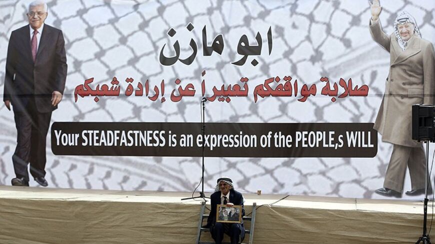 A Palestinian sits in front of a poster depicting Palestinian President Mahmoud Abbas (L) and late Palestinian leader Yasser Arafat during a rally in the West Bank city of Ramallah March 17, 2014. Thousands of Palestinians took to the streets on Monday to show their support for President Mahmoud Abbas, who is under heavy pressure as he prepares to meet U.S. President Barack Obama. 
REUTERS/Mohamad Torokman (WEST BANK - Tags: POLITICS CIVIL UNREST) - RTR3HFEM