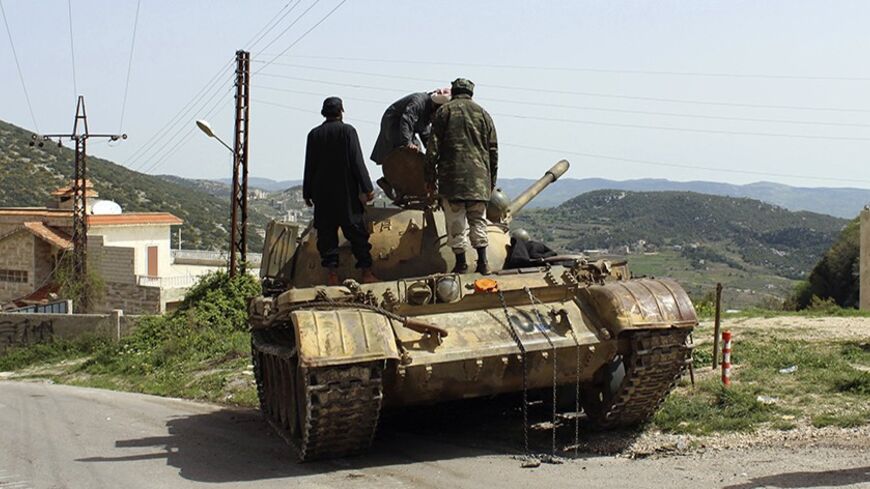 Free Syrian Army fighters stand on a tank at the Armenian Christian town of Kasab March 28, 2014. After months of setbacks in central Syria, Islamist rebels launched an offensive last Friday into the Latakia region, taking the border crossing and the Armenian Christian village of Kasab. The border crossing at Kasab they seized had been the last point of entry from Turkey into territory fully under control of Assad's forces, since most of the northern border region is already under rebel control. REUTERS/Str