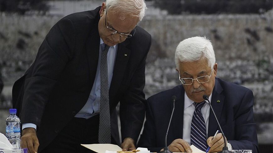 Palestinian chief negotiator Saeb Erekat (L) helps Palestinian President Mahmoud Abbas as he signs international conventions during a meeting with Palestinian leadership in the West Bank City of Ramallah April 1, 2014. Abbas signed more than a dozen international conventions on Tuesday citing anger at Israel's delay of a prisoner release, in a move jeopardised U.S. efforts to salvage fragile peace talks. REUTERS/Mohamad Torokman (WEST BANK - Tags: POLITICS) - RTR3JIOF