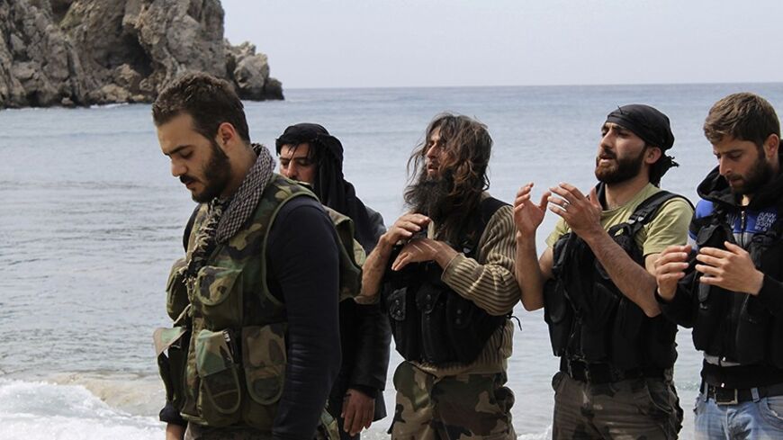 Rebel fighters pray at the beach of al-Samra in Latakia province near the town of Kasab March 31, 2014. The Turkish military fired back into Syria on Monday in retaliation for mortar shells and a rocket from over the border that hit a mosque in the town of Yayladagi, the provincial governor's office and local media said. Three mortar rounds landed on Turkish soil, fired during fighting between the Islamist rebels in Syria and forces loyal to Syrian President Bashar al-Assad for control of the Armenian Chris