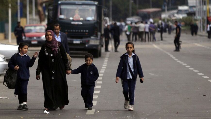 A woman walks with her children past police officers near the site of a series of explosions in front of Cairo University April 2, 2014. The series of explosions outside Cairo University killed two people on Wednesday, including a police brigadier-general, security officials said, in what appeared to be the latest militant attack in a fast-growing insurgency. REUTERS/Amr Abdallah Dalsh (EGYPT - Tags: POLITICS CIVIL UNREST) - RTR3JMXQ