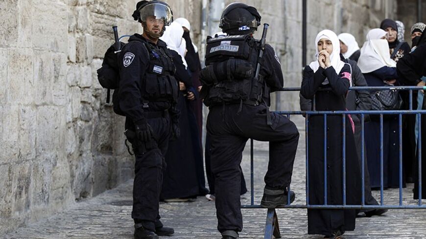 A Palestinian woman looks on as Israeli policemen prevent people from entering the compound which houses al-Aqsa mosque and is known to Muslims as Noble Sanctuary and to Jews as Temple Mount, in Jerusalem's Old City April 16, 2014. Israeli riot police entered one of Jerusalem's most revered and politically sensitive religious compounds on Wednesday to disperse rock-throwing Palestinians opposed to any Jewish attempts to pray there. REUTERS/Ammar Awad (JERUSALEM - Tags: POLITICS CIVIL UNREST RELIGION) - RTR3