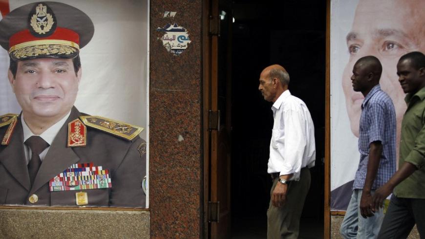 People walk past posters of presidential candidate and former army chief Abdel Fattah al-Sisi at one of his campaign headquarters in central Cairo April 16, 2014. Egyptians will vote on May 26-27 in a presidential election where Abdel Fattah al-Sisi is expected to win easily. REUTERS/Amr Abdallah Dalsh   (EGYPT - Tags: POLITICS ELECTIONS) - RTR3LLFL