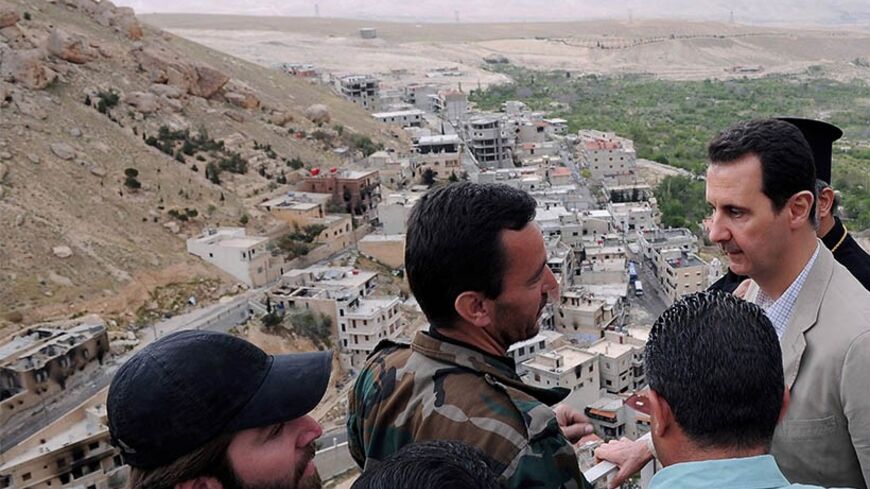 Syrian President Bashar al-Assad (R) speaks to a soldier during his visit to Maaloula town, northeast of Damascus April 20, 2014, in this handout photograph released by Syria's national news agency SANA. Assad on Sunday visited Maaloula, an ancient Christian town recaptured from rebels last week, state media said, as he seeks to persuade minorities that the government is their best protection against hardline Islamists. Assad's Easter visit to Maaloula - a rare appearance outside central Damascus - also hig