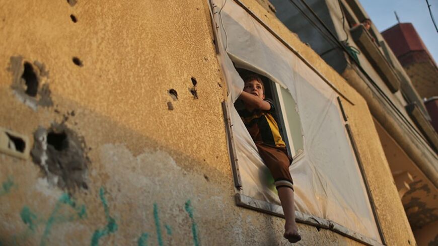 A Palestinian boy looks out through the window of his house at Shati refugee camp in Gaza City April 22, 2014. The Palestine Liberation Organization (PLO) sent a delegation to Gaza on Tuesday to negotiate unity with militant group Hamas for the first time since their 2007 conflict, potentially boosting Fatah leader and Palestinian president Mahmoud Abbas's position. REUTERS/Mohammed Salem (GAZA - Tags: POLITICS SOCIETY) - RTR3M9M9