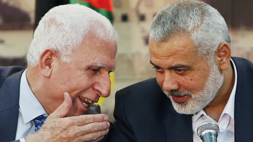 Senior Fatah official Azzam Al-Ahmed (L) speaks with head of the Hamas government Ismail Haniyeh as they announce a reconciliation agreement during a news conference in Gaza City April 23, 2014. The Gaza-based Islamist group Hamas and President Mahmoud Abbas's Palestine Liberation Organization (PLO) agreed on Wednesday to implement a unity pact, both sides announced in a joint news conference.REUTERS/Suhaib Salem (GAZA - Tags: POLITICS) - RTR3MC0Q