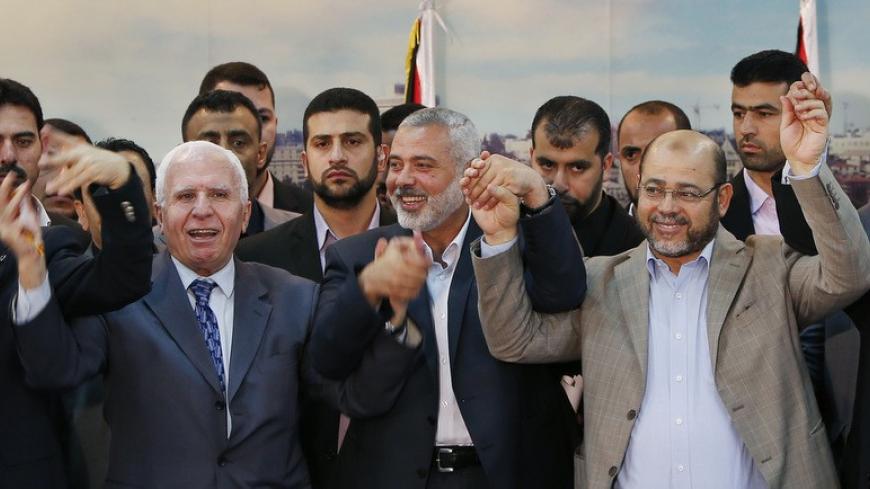 Senior Fatah official Azzam Al-Ahmed (L), head of the Hamas government Ismail Haniyeh (C) and senior Hamas leader Moussa Abu Marzouq hold their hands after announcing a reconciliation agreement in Gaza City April 23, 2014. The Gaza-based Islamist group Hamas and President Mahmoud Abbas's Palestine Liberation Organization (PLO) agreed on Wednesday to implement a unity pact, both sides announced in a joint news conference.REUTERS/Suhaib Salem (GAZA - Tags: POLITICS) - RTR3MC27