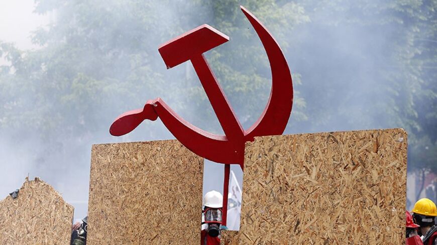 A protester holds a hammer and a sickle sign as he and others shield themselves from police during a May Day demonstration in Istanbul May 1, 2014. Turkish police fired water cannon and tear gas on Thursday to prevent hundreds of protesters from defying a ban on May Day rallies and reaching Istanbul's central Taksim Square, the focal point of weeks of protests last summer.         REUTERS/Murad Sezer (TURKEY  - Tags: POLITICS CIVIL UNREST)   - RTR3NDAF