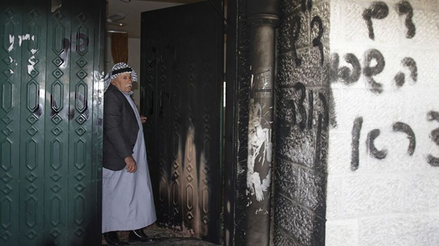 A Palestinian man stands near a door and wall of a mosque which were vandalised in the West Bank village of Deir Istiya, near the Jewish settlement of Ariel January 15, 2014. The mosque in the north of the Israeli-occupied West Bank was partly set on fire on Wednesday, in what Palestinians residents said was an attack by Jewish settlers living nearby. The main gate of the mosque and some of the carpeting inside were charred by the flames. Graffiti in Hebrew, reading "Revenge for spilled blood" and "Arabs Ou