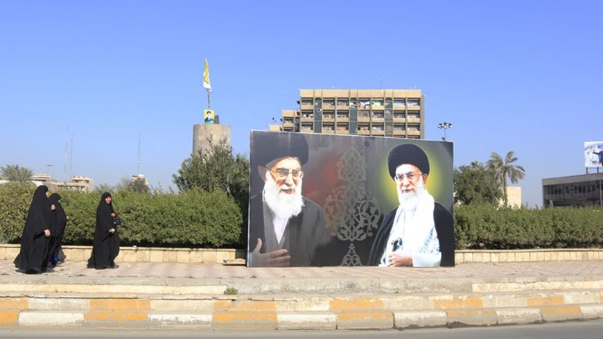 Iraqi women walk towards a poster depicting images of Shi'ite Iran's Supreme Leader Ayatollah Ali Khamenei at al-Firdous Square in Baghdad February 12, 2014. An Iraqi daily newspaper stopped publishing after two bombs were planted in the entrance to its headquarters in Baghdad on Monday and after threats from an Iranian-backed Shi'ite militia. Editors and reporters at Assabah AlJadeed said they had received death threats from the influential Asaib al-Haq militia in response to what it had described as an "i