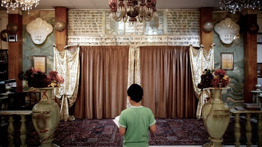 An Iranian Jewish boy reads the holy Torah at a synagogue in downtown Tehran on September 24, 2013. Present for more than 2,500 years in Persia, Iranian Jews have lost more than 70 percent of their 80,000 to 100,00 population of before the 1979 Islamic revolution and now Iran is home to some 8,750 Jews, according to a 2011 census, but it could also go up to 20,000. They are scattered across the country, but are mostly in the capital Tehran, Isfahan in the center, and Shiraz in the south. AFP PHOTO/BEHROUZ M