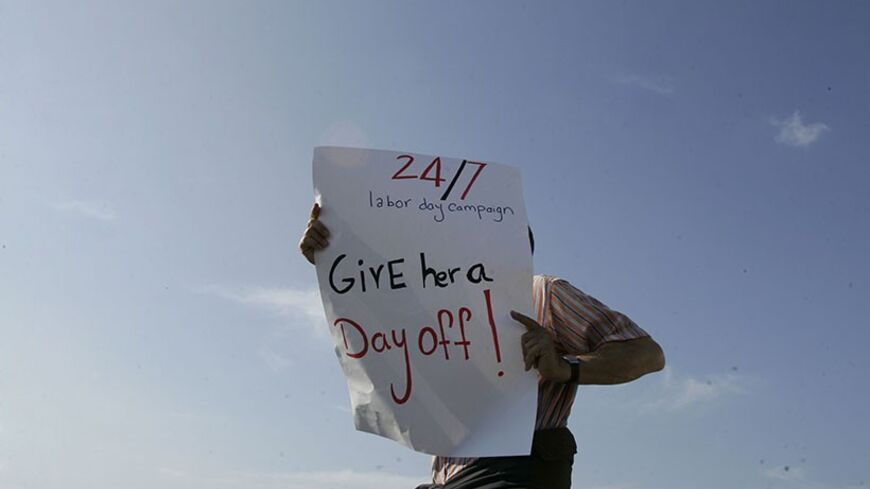 An activist holds up a banner during a demonstration to support the rights of migrant domestic workers in Lebanon, on the occasion of  Labor Day in Beirut, May 1, 2010. REUTERS/Cynthia Karam (LEBANON - Tags: CIVIL UNREST) - RTR2DCEX