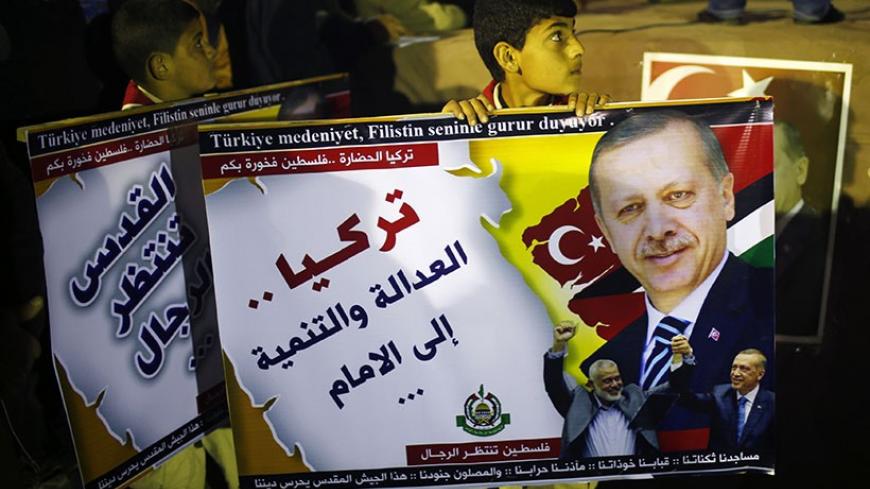 A Palestinian boy holds a poster of Turkish Prime Minister Tayyip Erdogan as he celebrates after Erdogan declared victory in local polls during a rally organised by Hamas movement in the northern Gaza Strip March 31, 2014. Erdogan declared victory in local polls that had become a referendum on his rule and said he would "enter the lair" of enemies who have accused him of corruption and leaked state secrets. The Arabic words read "Turkey Justice and development forward". REUTERS/Mohammed Salem (GAZA - Tags: 