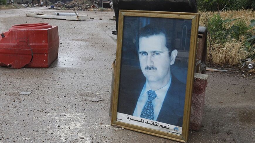 A photo of Syria's President Bashar al-Assad is seen along a street in old Homs city May 8, 2014. Syrian forces say they will take full control on Thursday over Homs, a city once vibrant with pro-democracy crowds but now associated with images of ruin that epitomise the brutality of Syria's civil war. After holding the Old City of Homs for nearly two years, close to 1,200 rebel fighters boarded buses which took them out of the "capital of the revolution" in convoys on Wednesday and Thursday, activists said.