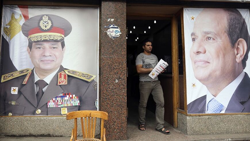 A volunteer leaves the headquarters of former Egyptian army chief Abdel Fattah al-Sisi near his poster in El Gamaliya district, where he spent his childhood, in the old Islamic area of Cairo May 9, 2014. As the Egyptian state presses its crackdown on the Muslim Brotherhood, the man expected to become president has deployed a new weapon in the battle with the Islamists: his own vision of Islam. Sisi, the former army chief who deposed the Brotherhood's Mohamed Mursi and is expected to be elected president lat