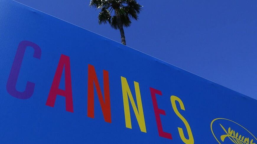 A palm tree is seen above a poster of the 67th Cannes Film Festival near the Port of Cannes on the eve of the opening of the Festival in Cannes May 13, 2014. The festival will run from May 14 to 25.        REUTERS/Yves Herman (FRANCE  - Tags: ENTERTAINMENT)   - RTR3OWVU