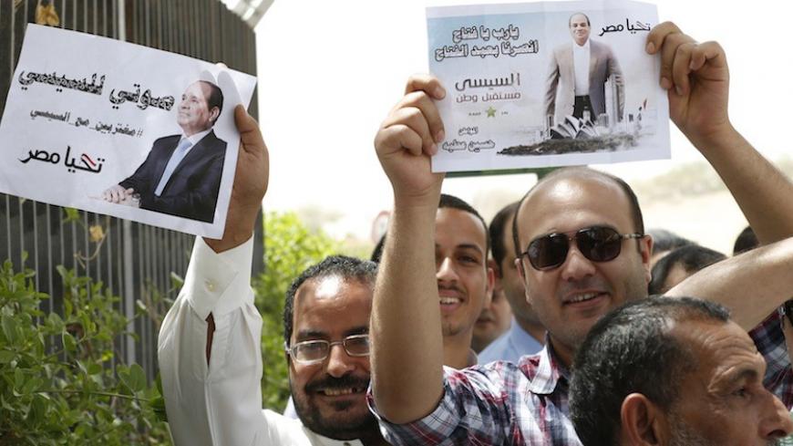 Egyptians hold pictures of Egypt's presidential candidate and former army chief Abdel Fattah al-Sisi as they wait to cast their votes for the presidential election at the Egyptian embassy in Riyadh May 15, 2014. Egyptians living outside the country on Thursday began voting in the presidential election, which will be held on May 26-27 in Egypt. REUTERS/Faisal Al Nasser (SAUDI ARABIA - Tags: POLITICS ELECTIONS) - RTR3PAN1