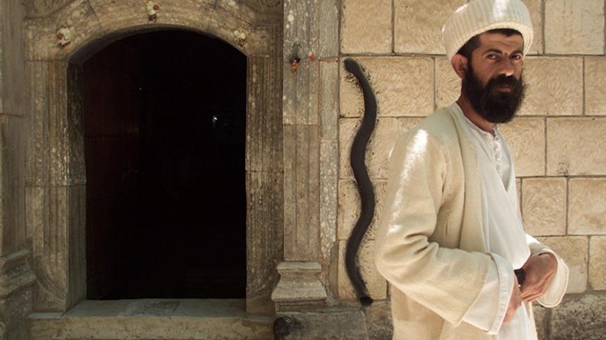 Yezidi monk Baba Chawish poses in front of an entrance to the Lalish
temple some 50 km north from Iraqi city of Mosul, May 11, 2003. The
Yezidi religion, seen by its followers as the original Kurdish faith,
is believed to date back several thousand years and blends ideas from
sources as diverse as Zoroastrianism, Islam and Christianity.
REUTERS/Shamil Zhumatov REUTERS

SZH/AS - RTRNBPT