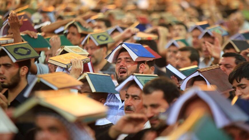 Shi'ite people place copies of the Koran on their heads during a ceremony marking the death anniversary of Imam Ali at his shrine in the holy city of Najaf, about 160 km (100 miles) south of Baghdad, July 30, 2013. Imam Ali, the son-in-law of Prophet Mohammad, was wounded in the head during a battle and died after two days in 661 AD in Najaf. REUTERS/Ahmad Mousa (IRAQ - Tags: RELIGION TPX IMAGES OF THE DAY)     FOR BEST QUALITY IMAGE ALSO SEE: GM1EA3R14QL01 - RTX124BU