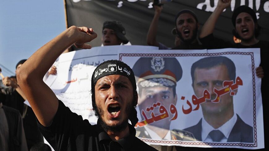 A Palestinian Salafist shouts slogans in front of a poster depicting Syria's President Bashar al-Assad (R) and Egypt's army chief General Abdel Fattah al-Sisi with the Arabic words that read "criminals and murderers", during a rally in protest of what they say are recent massacres committed against Syrian and Egyptian people, in Rafah in the southern Gaza Strip August 22, 2013. REUTERS/Ibraheem Abu Mustafa (GAZA - Tags: POLITICS CIVIL UNREST TPX IMAGES OF THE DAY) - RTX12TC6