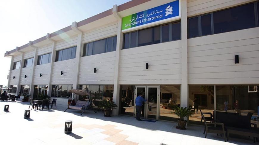 An employee of the Standard Chartered bank enters the bank in Baghdad, December 1, 2013. British lender Standard Chartered  launched banking operations in Iraq on Wednesday, saying it hoped to benefit from large infrastructure projects in a country trying to rebuild after years of conflict.  REUTERS/Ahmed Saad    (IRAQ - Tags - Tags: BUSINESS) - RTX15ZHF
