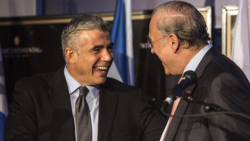 Secretary-General of the Organisation for Economic Co-operation and Development (OECD) Jose Angel Gurria (R) shakes hands with Israel's Finance Minister Yair Lapid at the end of a news conference in Tel Aviv December 8, 2013. The Bank of Israel should prepare for interest rate increases once the global economy returns to normal, the OECD said. REUTERS/Nir Elias (ISRAEL - Tags: POLITICS BUSINESS) - RTX169RL