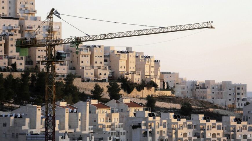 A crane is seen next to homes in a Jewish settlement near Jerusalem known to Israelis as Har Homa and to Palestinians as Jabal Abu Ghneim January 3, 2014. Israel on Friday published tenders for 1,400 new homes in the occupied West Bank and East Jerusalem, days after U.S. Secretary of State John Kerry visited the region to push peace efforts with the Palestinians. Picture taken January 3, 2014. REUTERS/Ammar Awad (BUSINESS CONSTRUCTION POLITICS) - RTX178IM