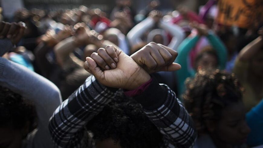 An African migrant gestures during a protest, held by women and children of the migrant community, against Israel's detention policy toward migrants, in Tel Aviv January 15, 2014. Israel has recently passed a law allowing for indefinite detention of migrants without valid visas while it pursues efforts to persuade them to leave or enlist other countries to take them in. REUTERS/Ronen Zvulun (ISRAEL - Tags: POLITICS SOCIETY IMMIGRATION CIVIL UNREST) - RTX17F7H
